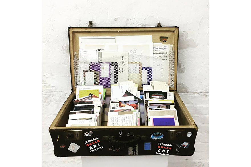 black opened up suitcase containing images, letters, postcards