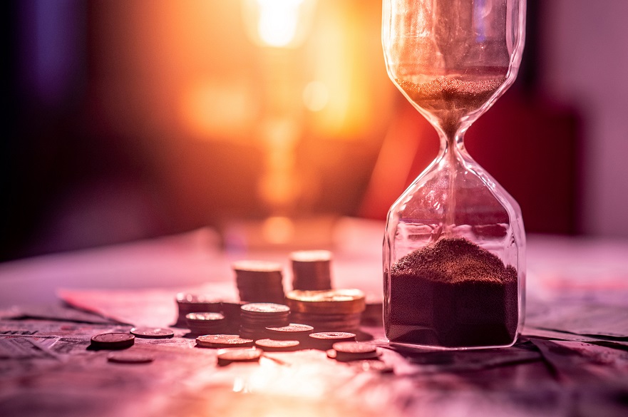 Sand timer with coins next to it