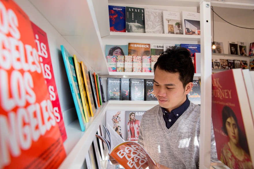 Student reading a book in a store in front of a shelves of books