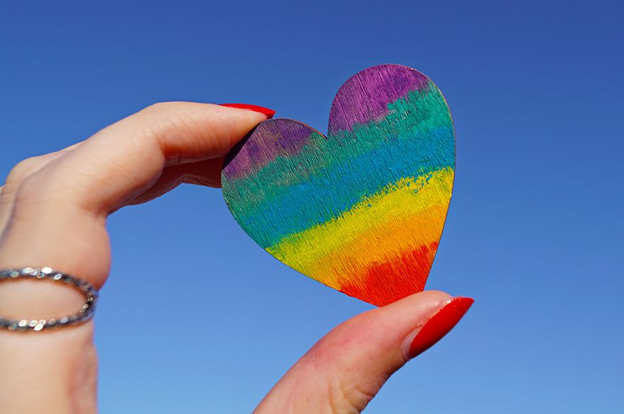 A hand holding a heart-shaped piece of wood. 