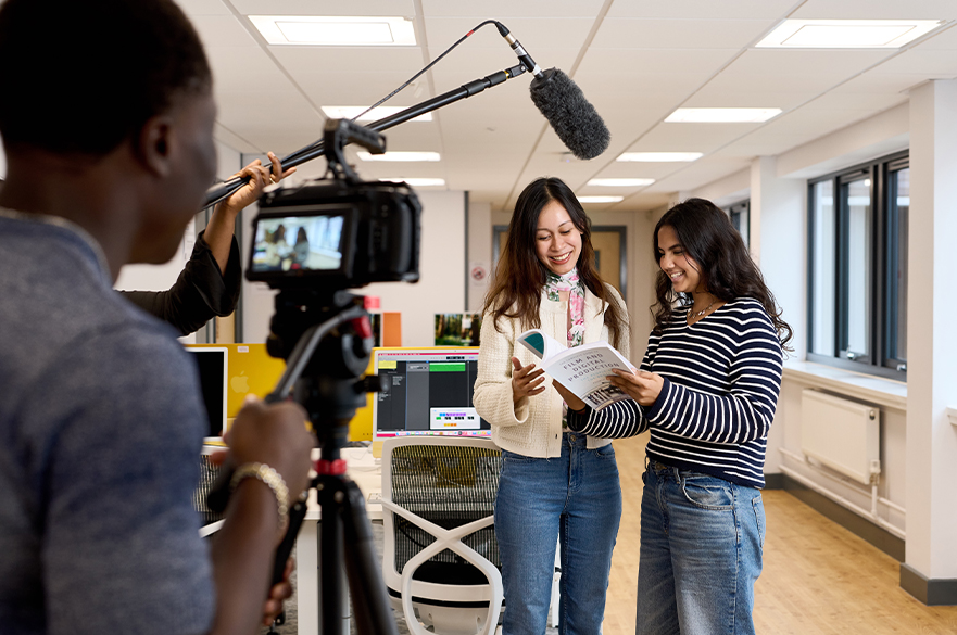 Two students reading a book and being interviews using NTU's specialised media equipment