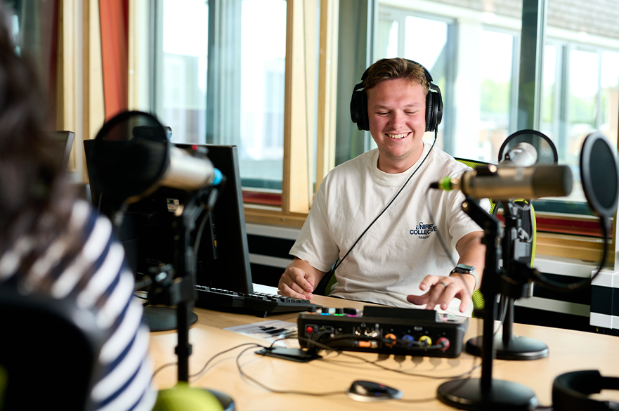 Journalism studio smiling and using the podcasting equipment at NTU