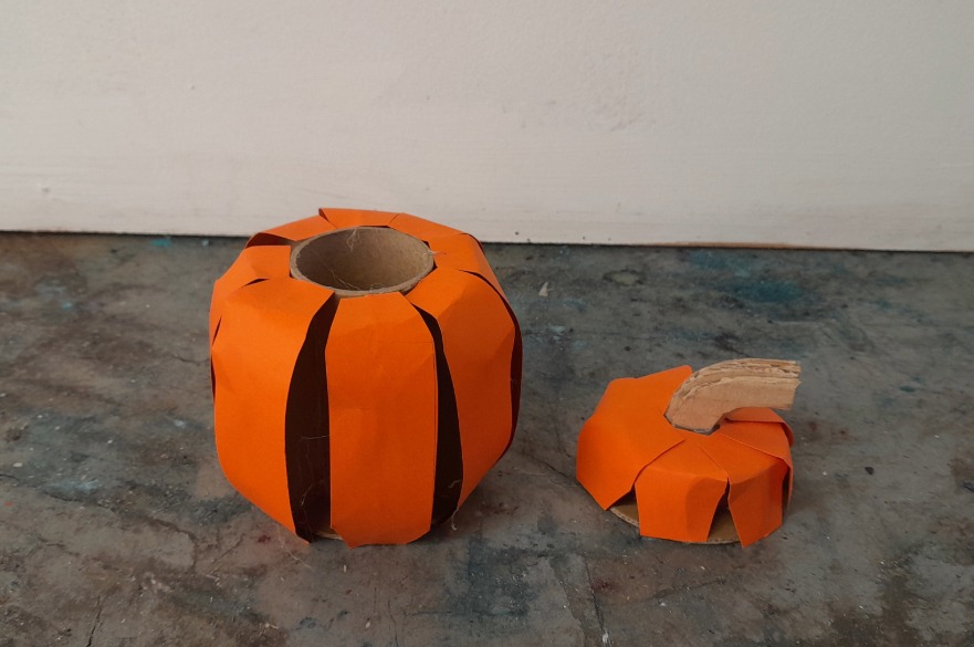 An orange pumpkin made of carboard.