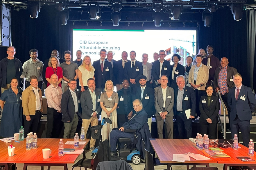 A group of people at a symposium having a group photo taken.