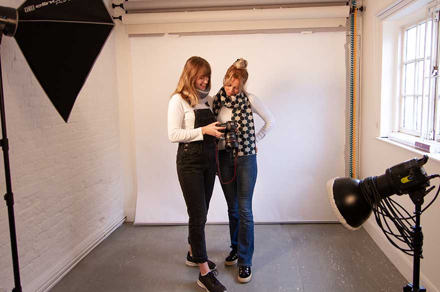 Photography alumna Elee and Fashion Marketing and Branding student Hannah collaborating in the photography studio