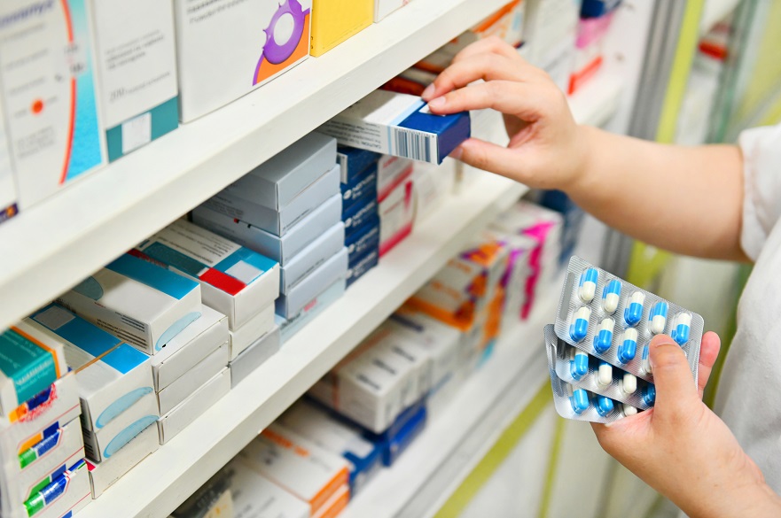 Pharmacist taking boxes of tablets off a shelf