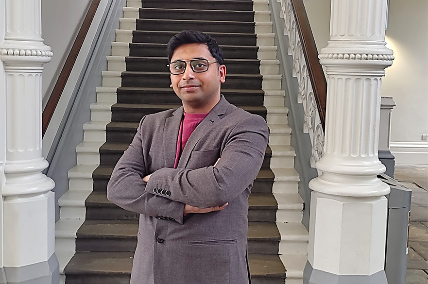 Dipro posing for the camera with his arms crossed in front of the staircase in the Arkwright building at NTU
