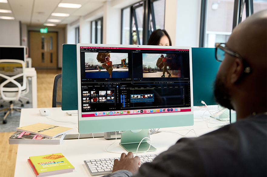 A student working on editing a video with some books on his desk