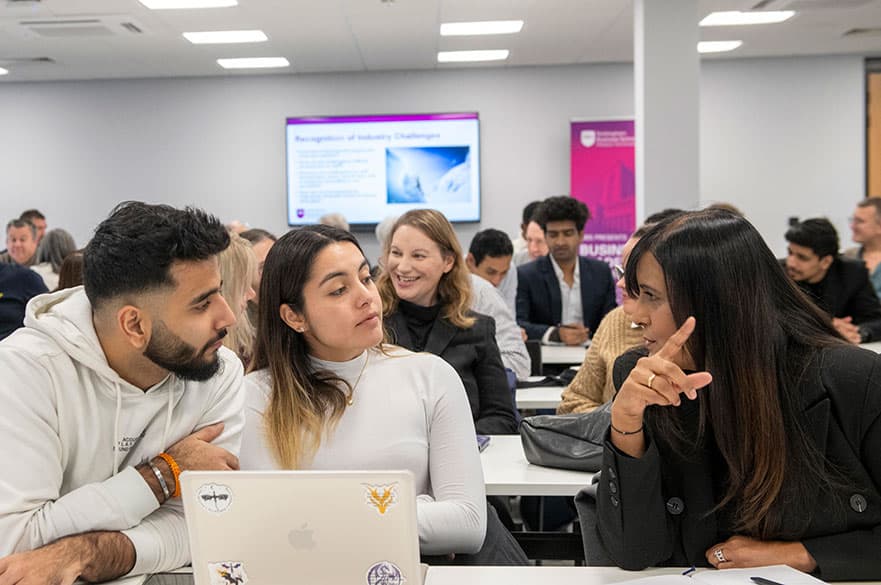 A group of MBA students having a discussion in a classroom.