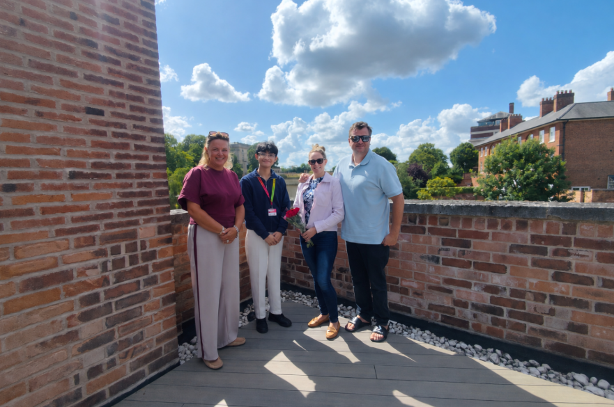 A design competition winner posed for a group photo with three other people in a rooftop garden.