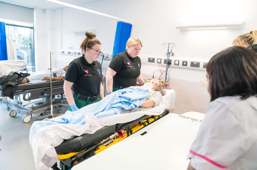 Student paramedics simulate moving a patient