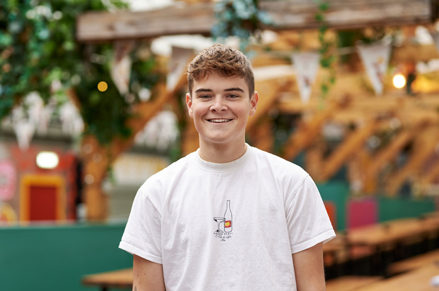 Student standing on NTU's campus and smiling at the camera