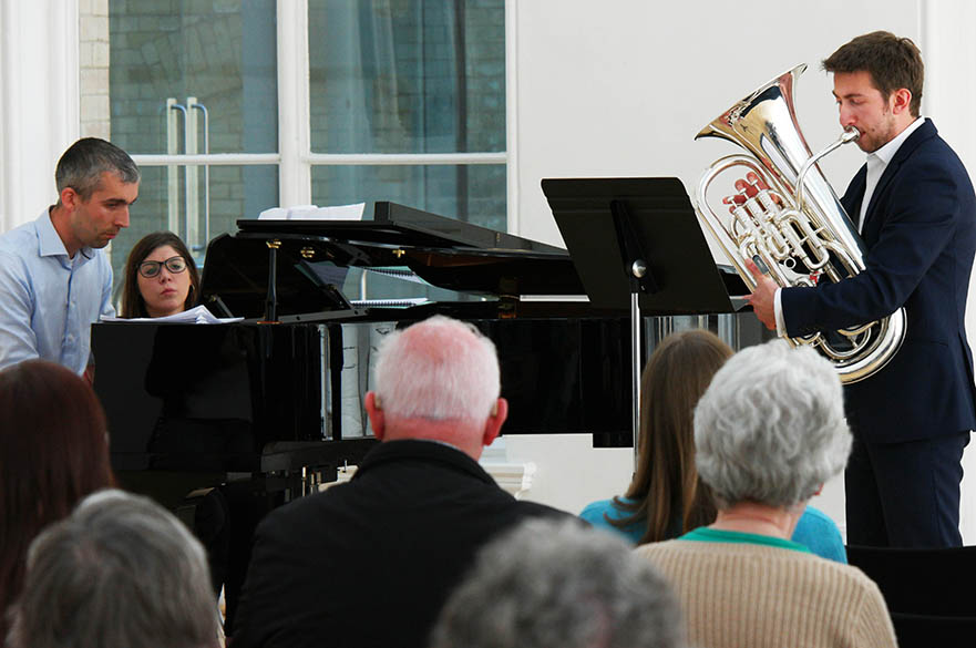 A male student playing a euphonium in front of an audience.