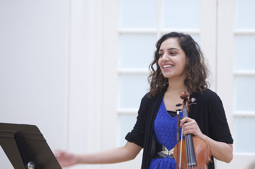 A female student stood at a music stand holding a violin.