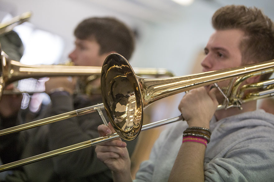 Male students playing the trombone.