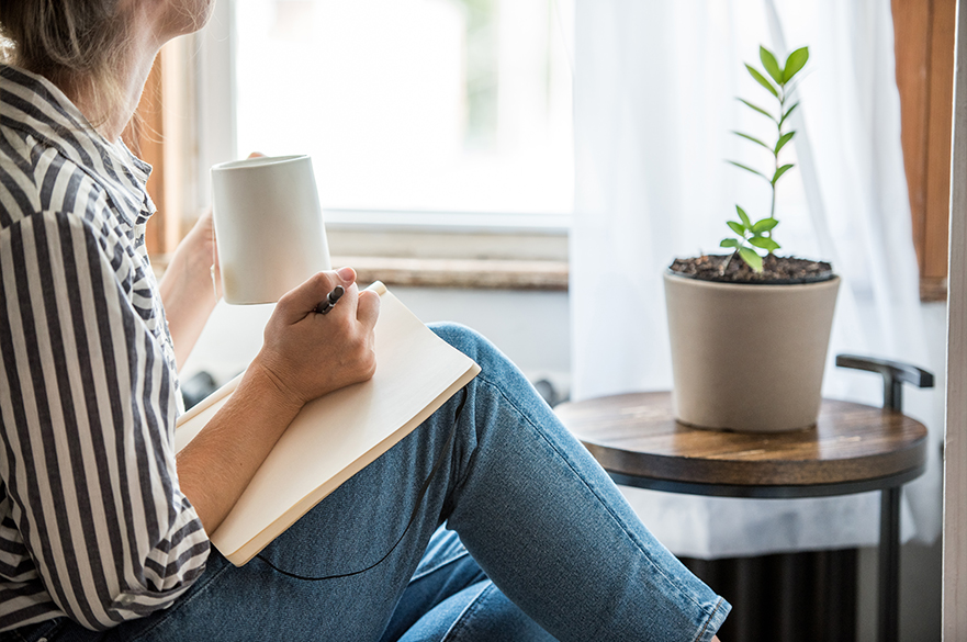 A female student sat with a notebook on her knee and a mug in her hand.