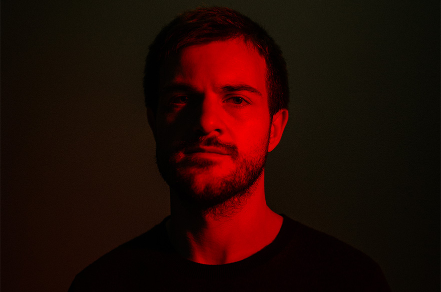 A man in a red tinted room looking at the camera