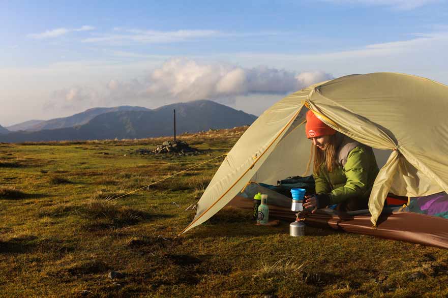 Woman in a tent making a coffee using a portable coffee maker