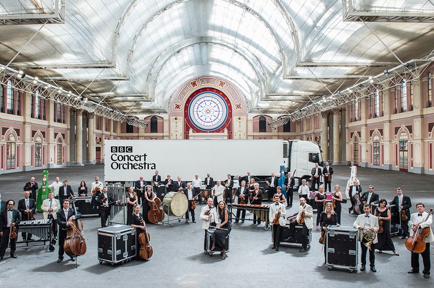 Musicians stood with their instruments in a grand hall.