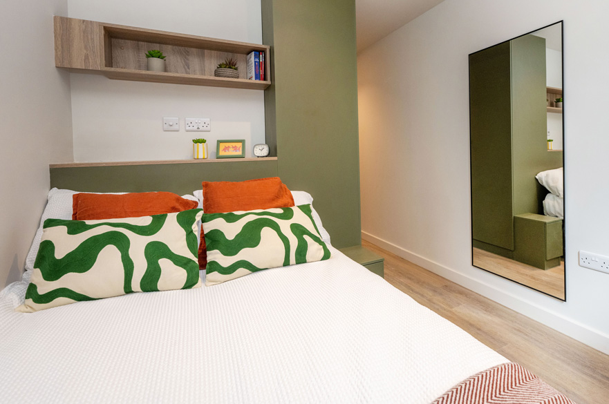 Classic Ensuite in Centre Court featuring a double bed with shelving above and a large mirror on the wall opposite.