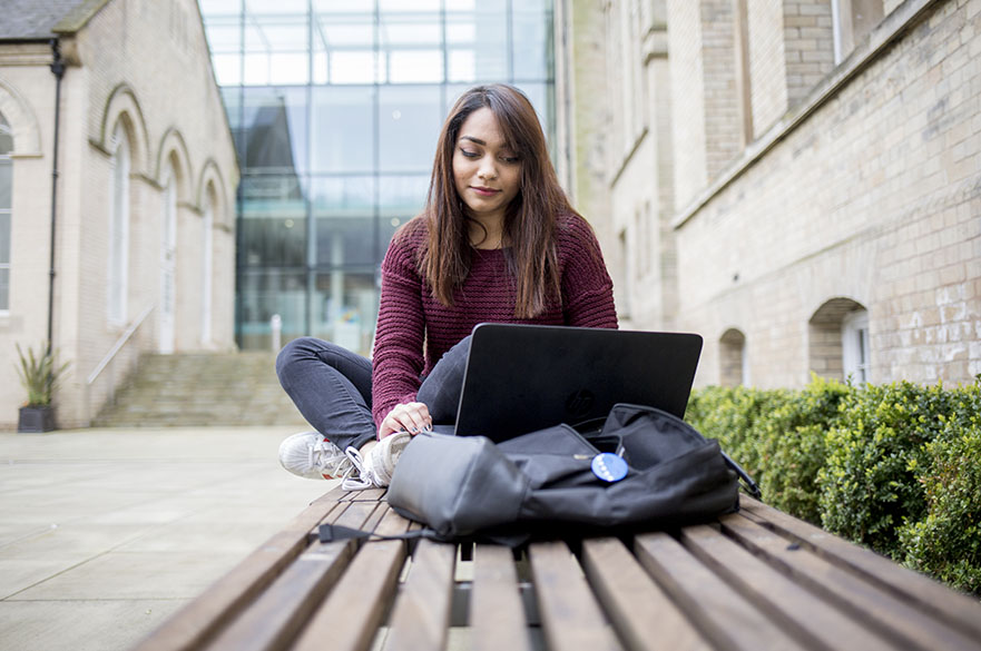 Student using a laptop in the Courtyard