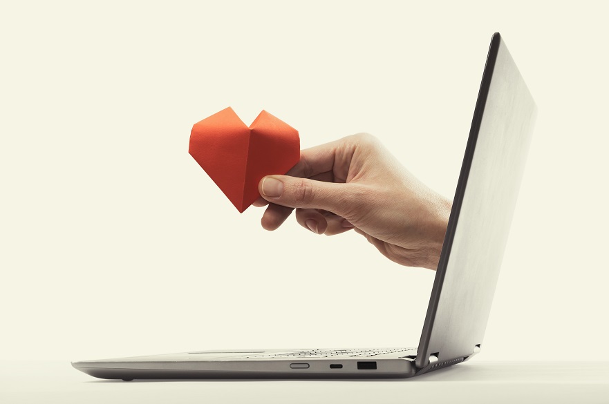 Hand holding a heart out of a computer screen