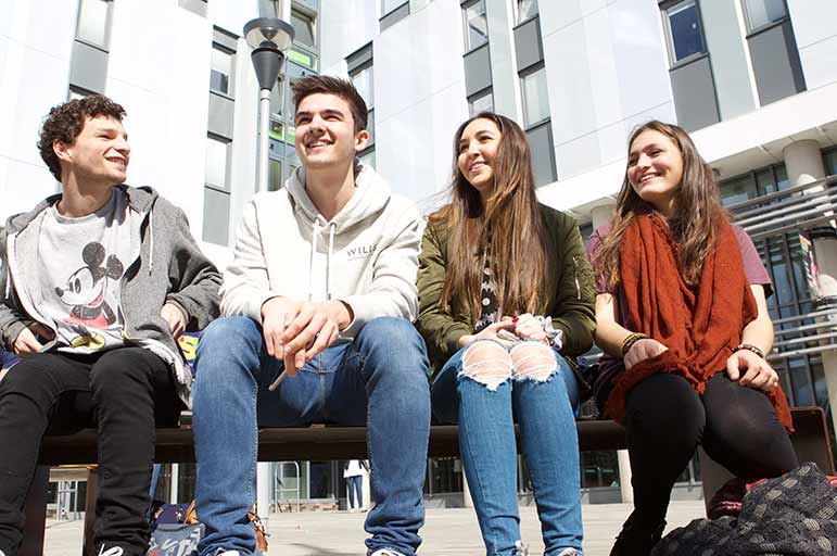 a group of happy students sitting outside together