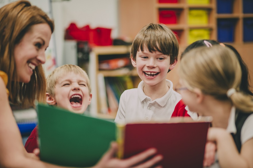 Children and teacher looking at a book