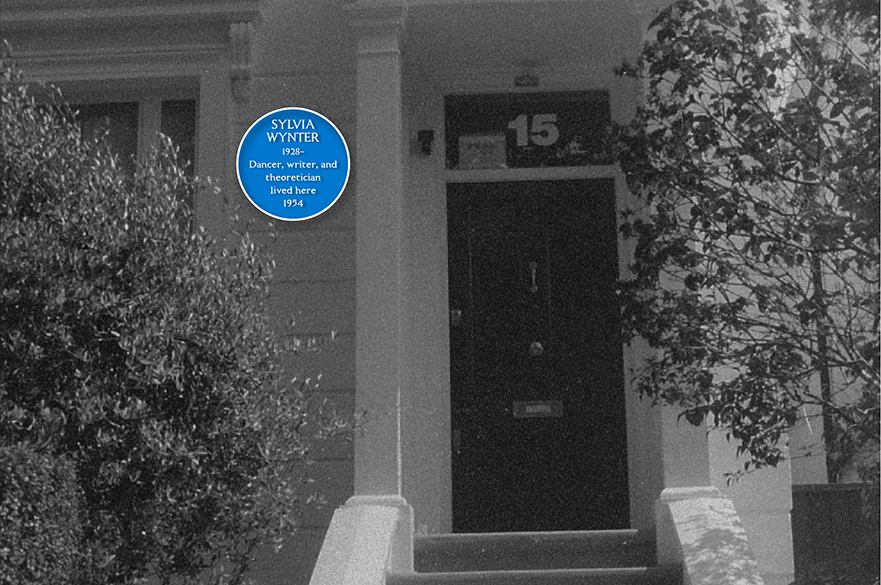 A blue plaque on a black and white building.