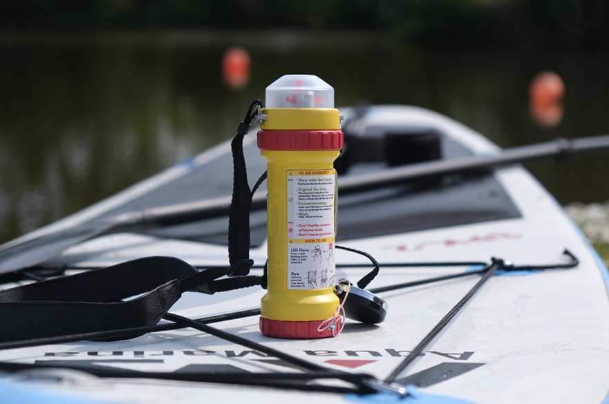 A safety device called PaddleLume placed on top of a paddleboard on a stretch of water.