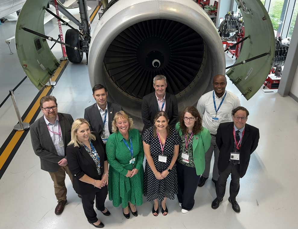 Representatives from NTU and ASI gather in front of an airplane engine at ASI Newark