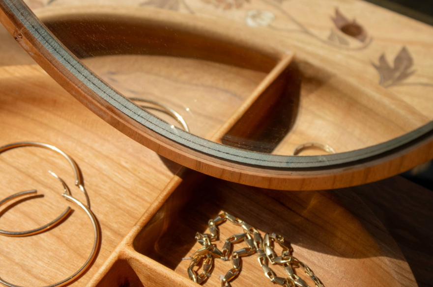 Someone putting jewellery into a drawer in a vanity table.