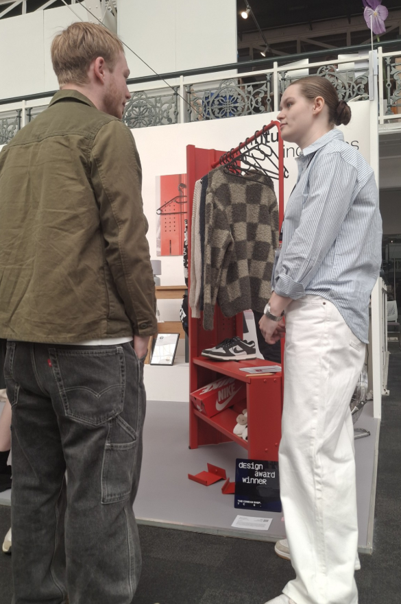 Two people talking at an exhibition of graduate design work.