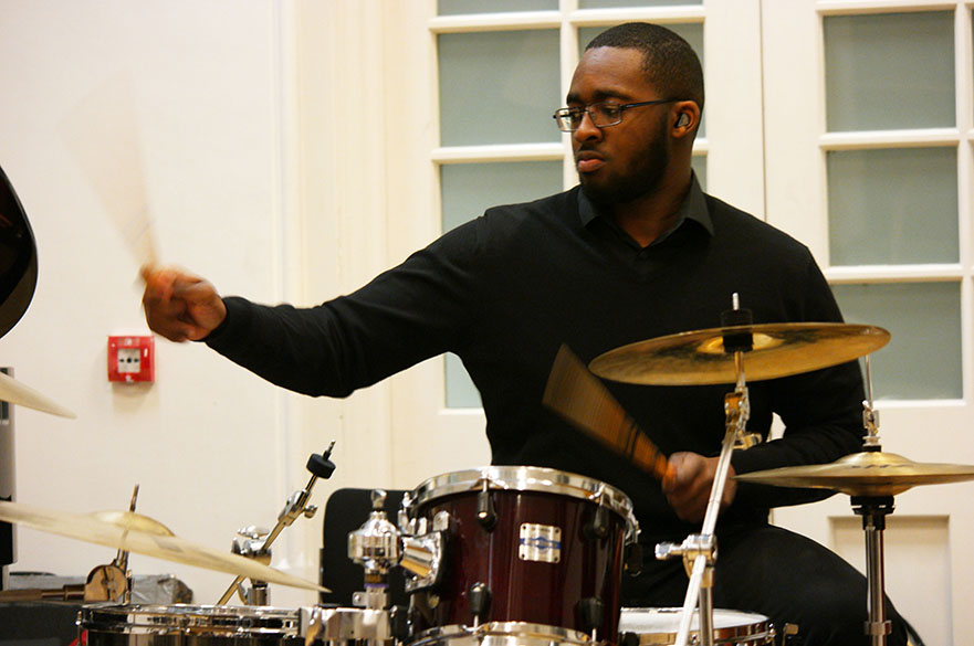 A male student playing the drum kit.