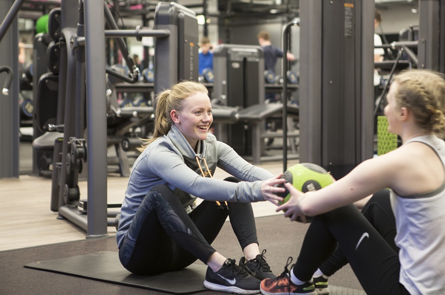 Females using medicine ball in gym together