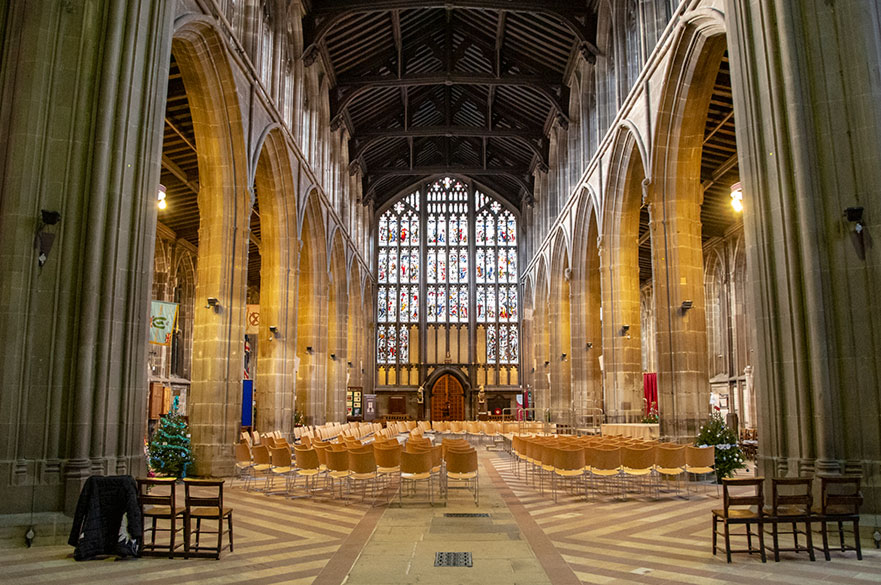 interior shot of church looking towards a door with large stained glass windows above it