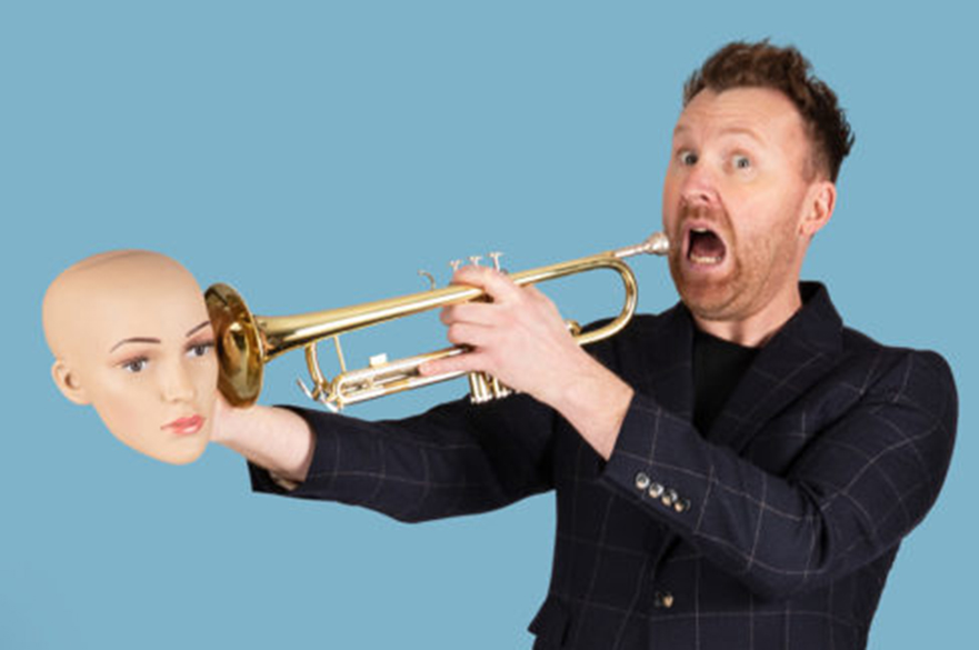 A man holding a trumpet and a dolls head.