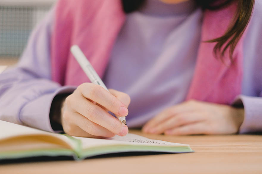 Hands writing in a notebook.