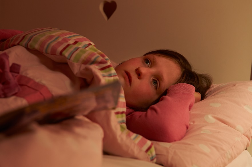 Young girl lying awake in bed