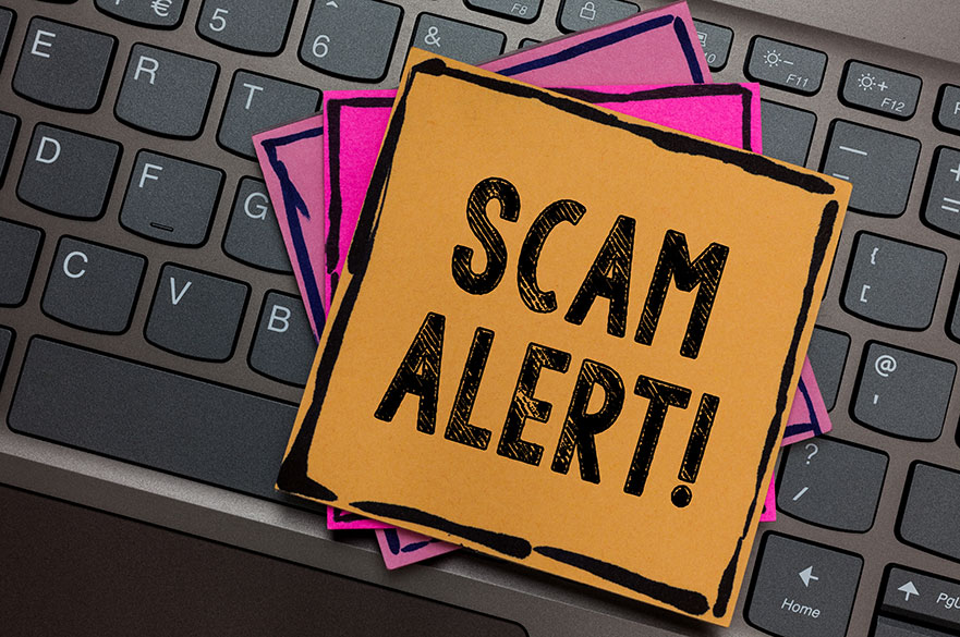 Post it notes on a keyboard with scam alert written on them