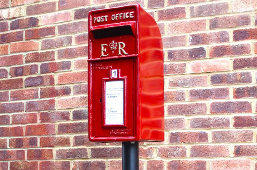 A red post-box against a brick wall.