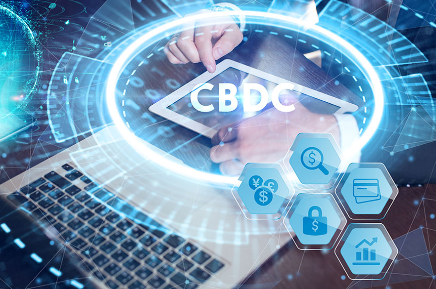 CBDC Central Bank Digital Currency Concept with hands on a tablet next to a laptop with finance icons surrounding