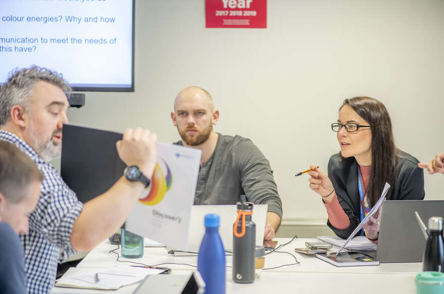Group of adults in a seminar room discussing a document