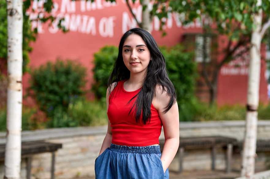Student standing on NTU's campus and smiling at the camera