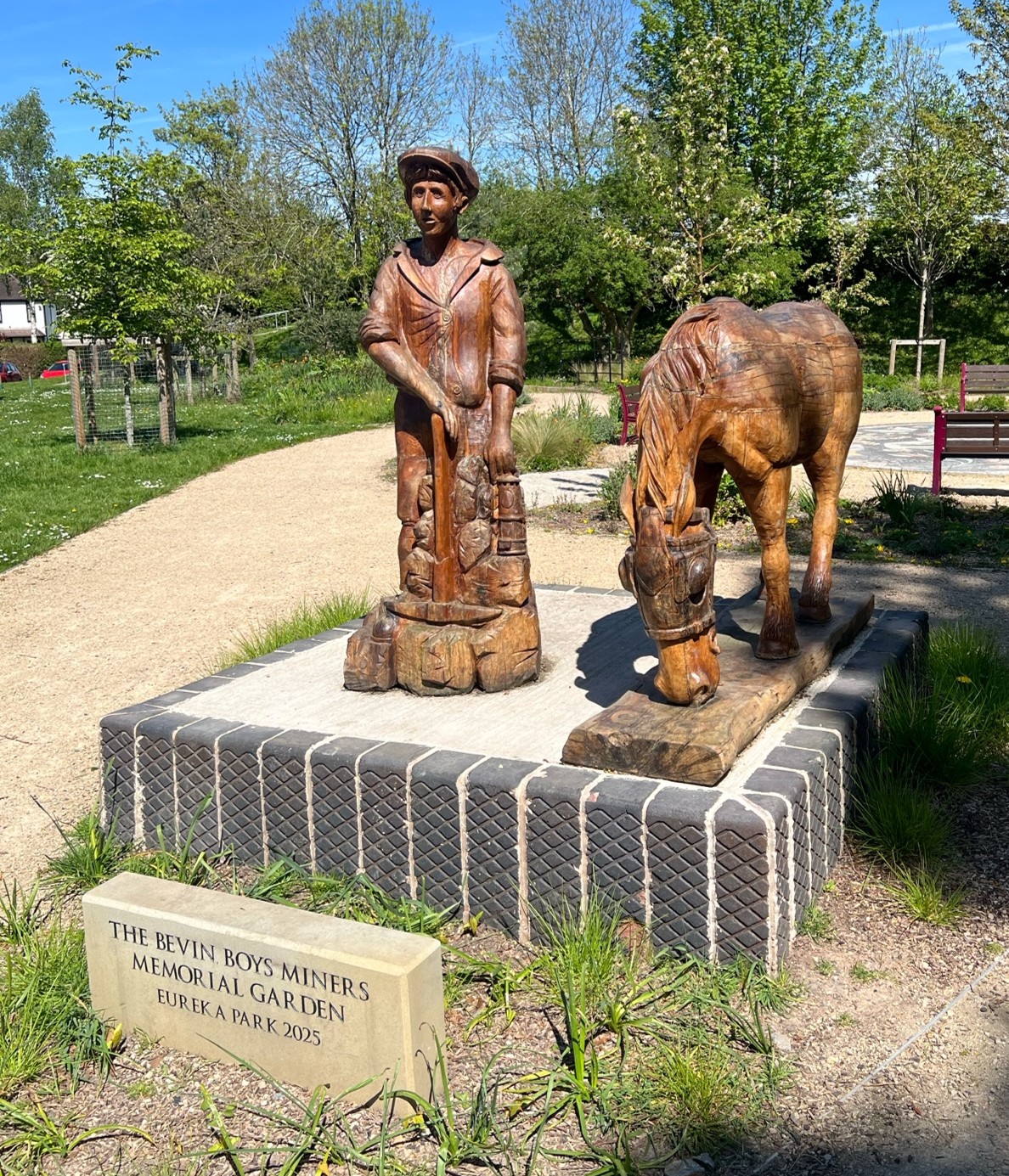A photo of the Bevan Boys Memorial Garden showing a bronze statue of a woman in a garden