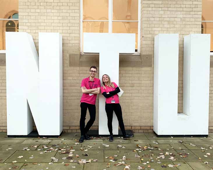 two people standing against NTU logo