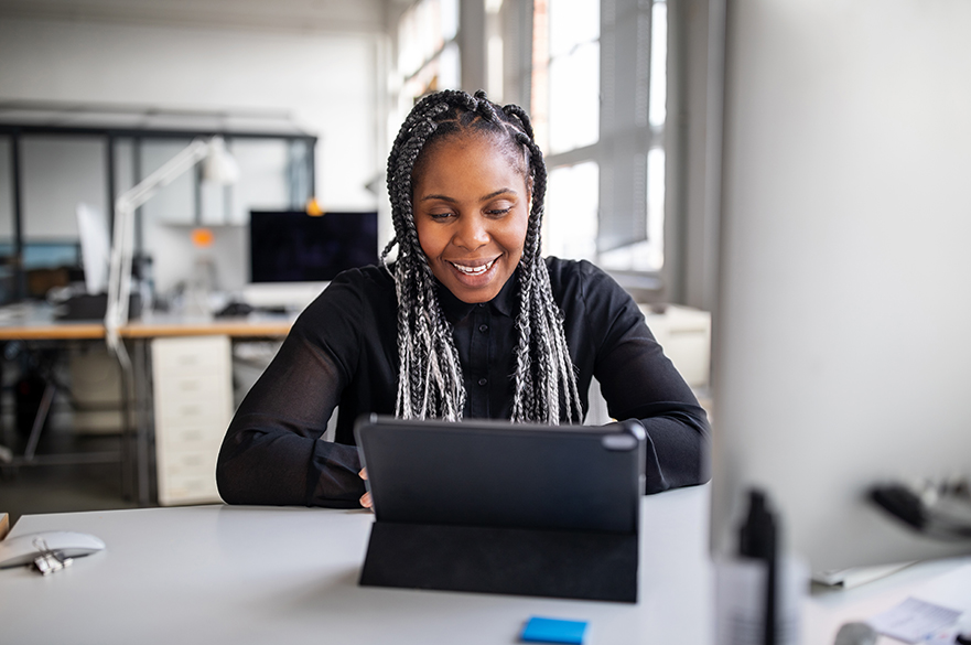 A women sat at a table looking at an iPad.