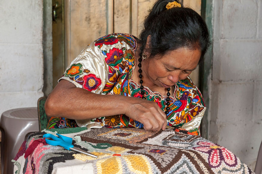 A woman weaving some colourful textiles.