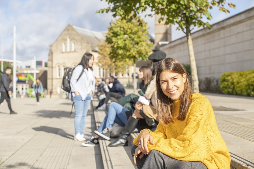 Student smiling on steps outside Newton building.