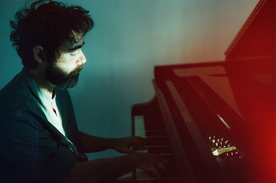 A man playing the piano in a blue and red lighted room